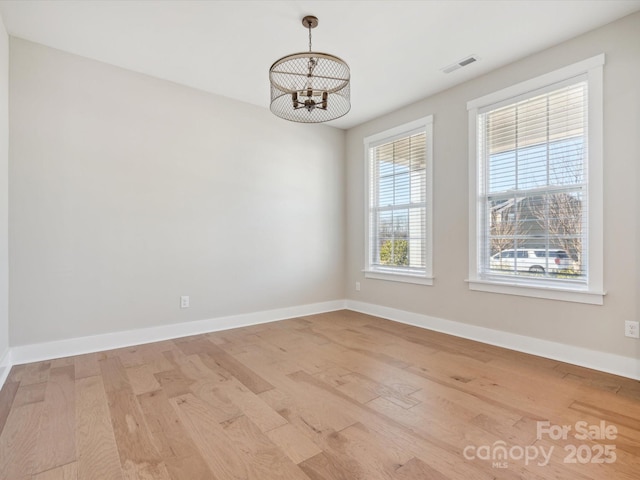 unfurnished room featuring light hardwood / wood-style flooring and a chandelier