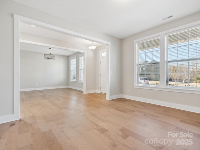 unfurnished room featuring light hardwood / wood-style floors and a notable chandelier