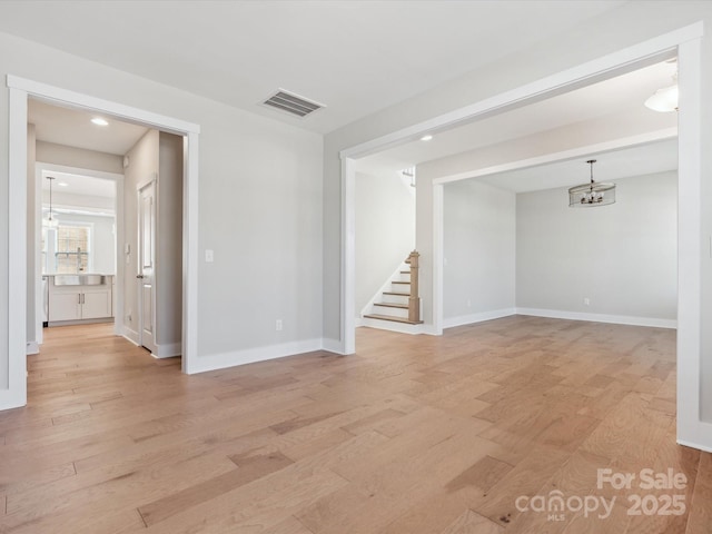 unfurnished room with light hardwood / wood-style floors, a notable chandelier, and sink