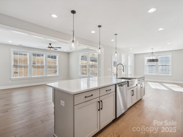 kitchen featuring a kitchen island with sink, dishwasher, ceiling fan, and decorative light fixtures