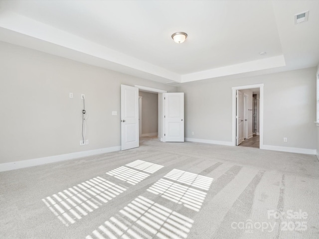 unfurnished bedroom with a tray ceiling and light carpet