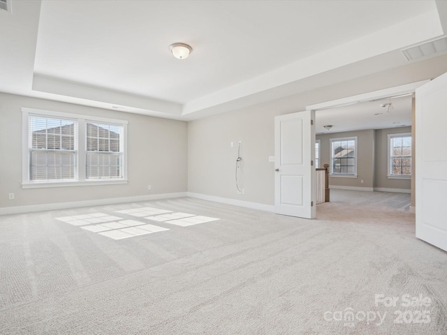 carpeted empty room with a tray ceiling