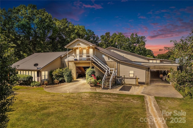 rear view of house with a patio, stairway, driveway, and a lawn