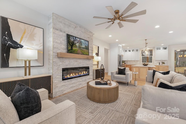 living room featuring light wood-style floors, ceiling fan, a fireplace, and recessed lighting