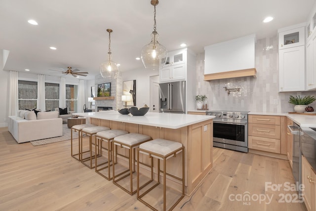 kitchen featuring premium appliances, tasteful backsplash, custom range hood, open floor plan, and light wood-type flooring