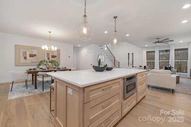 kitchen featuring recessed lighting, light countertops, stainless steel microwave, light wood-style flooring, and a kitchen island