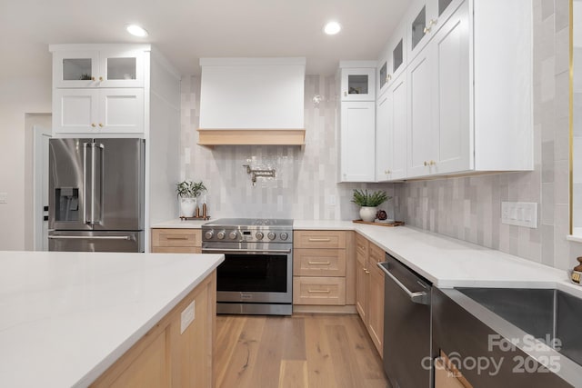 kitchen featuring recessed lighting, backsplash, appliances with stainless steel finishes, light wood-type flooring, and premium range hood