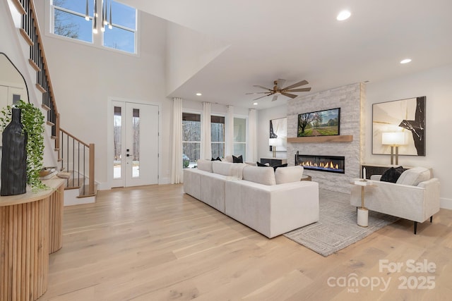 living area featuring ceiling fan, light wood-style flooring, recessed lighting, french doors, and stairway