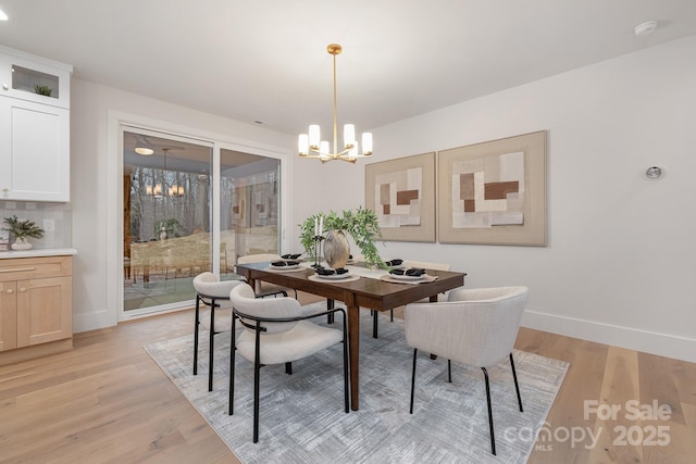 dining room with baseboards, light wood finished floors, and an inviting chandelier