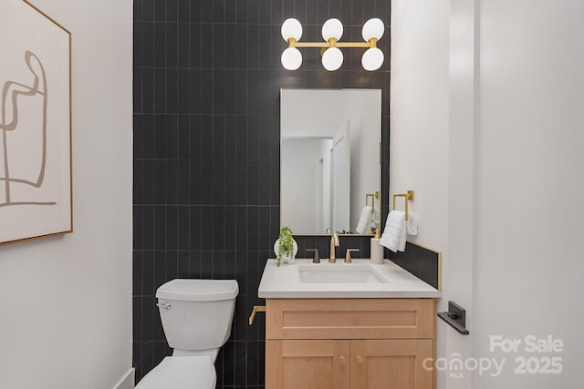 bathroom with toilet, tile walls, and vanity