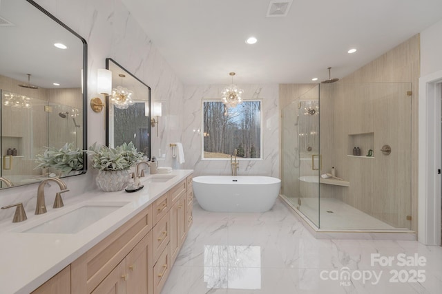 bathroom featuring marble finish floor, a soaking tub, visible vents, a sink, and a shower stall