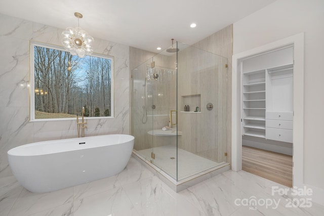 full bath featuring recessed lighting, a freestanding bath, marble finish floor, a shower stall, and a walk in closet