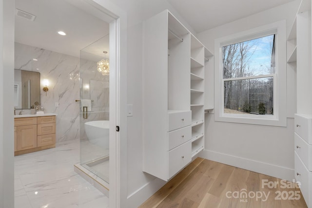 walk in closet with light wood-type flooring, visible vents, and a sink