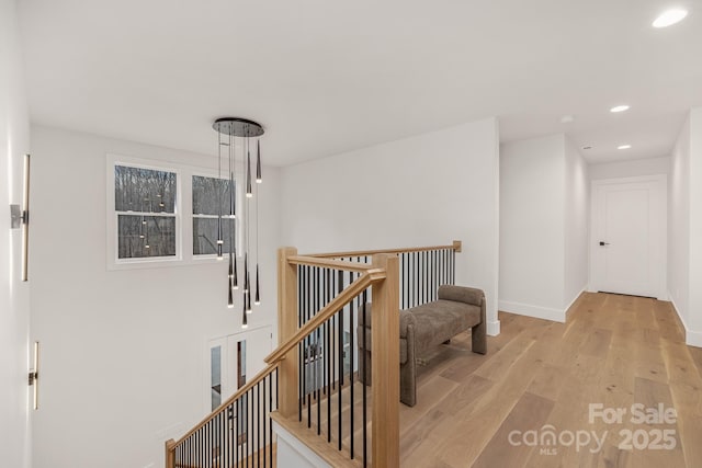 corridor with recessed lighting, baseboards, light wood finished floors, and an upstairs landing