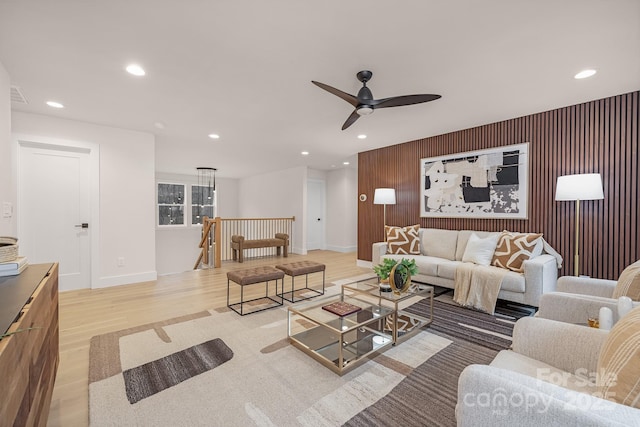 living area with an accent wall, visible vents, wood finished floors, and recessed lighting