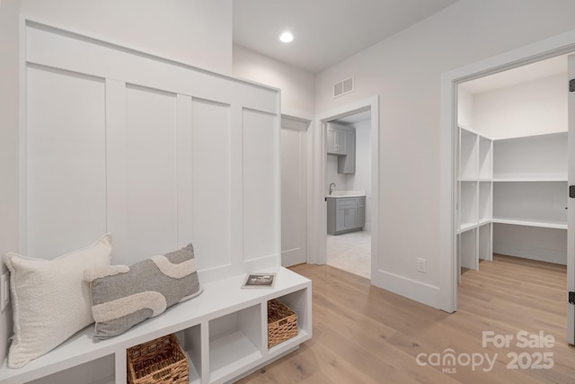 mudroom with baseboards, visible vents, light wood-type flooring, a sink, and recessed lighting