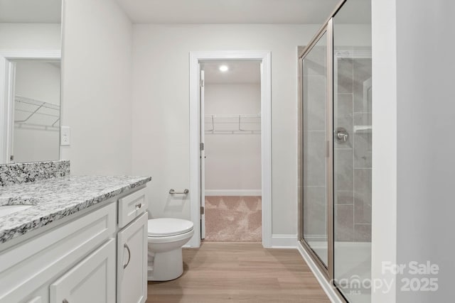 bathroom featuring hardwood / wood-style floors, vanity, toilet, and a shower with shower door