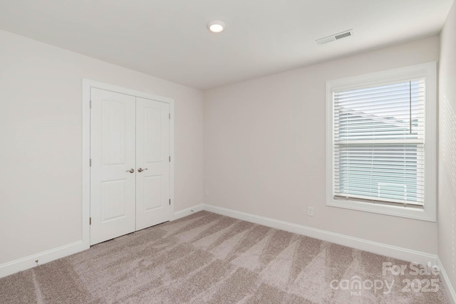 unfurnished bedroom featuring light colored carpet and a closet