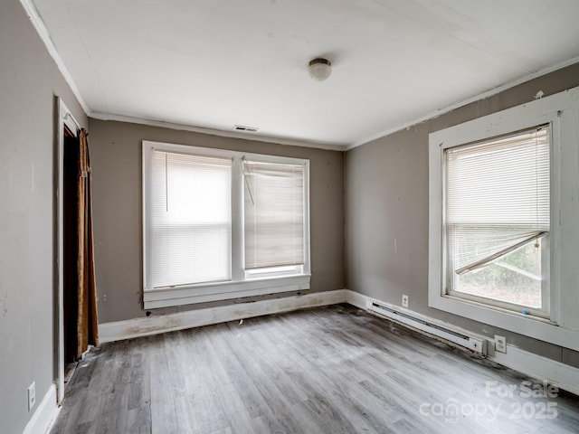 empty room featuring hardwood / wood-style floors, a baseboard heating unit, and ornamental molding