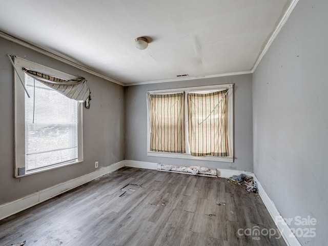 spare room with crown molding, plenty of natural light, and light hardwood / wood-style floors