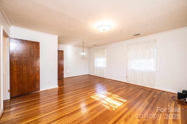 spare room with ornamental molding, wood-type flooring, and a notable chandelier