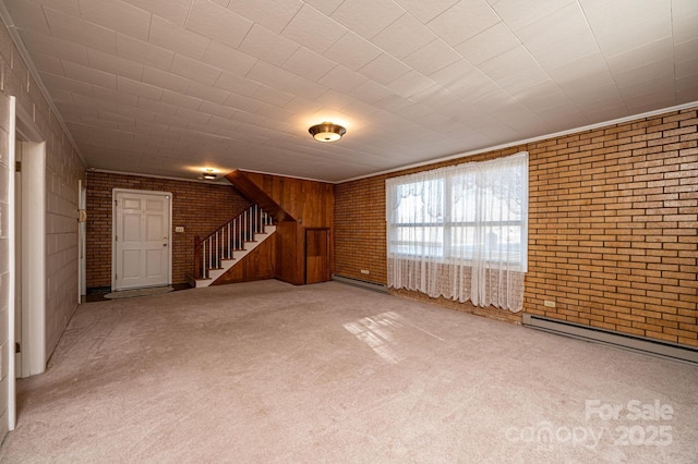 unfurnished living room with carpet, ornamental molding, a baseboard heating unit, and brick wall