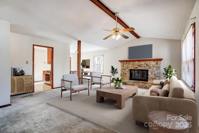 living room featuring ceiling fan, carpet, a stone fireplace, and vaulted ceiling with beams