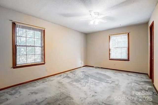 empty room featuring ceiling fan, light colored carpet, a wealth of natural light, and a textured ceiling