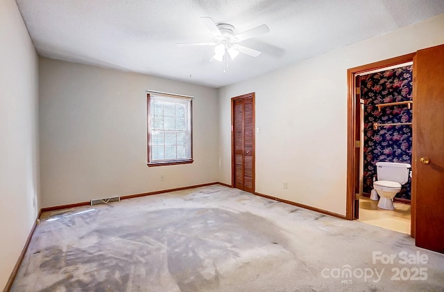 unfurnished bedroom with ceiling fan, carpet, ensuite bathroom, a textured ceiling, and a closet