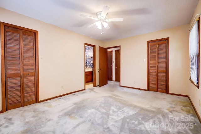 unfurnished bedroom with ceiling fan, two closets, and light colored carpet