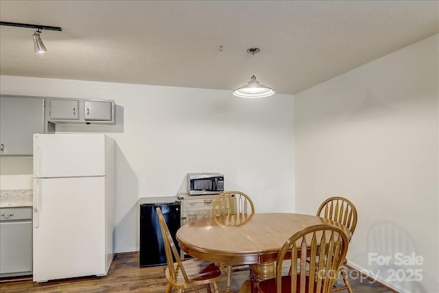 dining space with dark hardwood / wood-style flooring and a textured ceiling