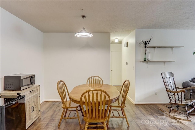 dining space with a textured ceiling and light wood-type flooring