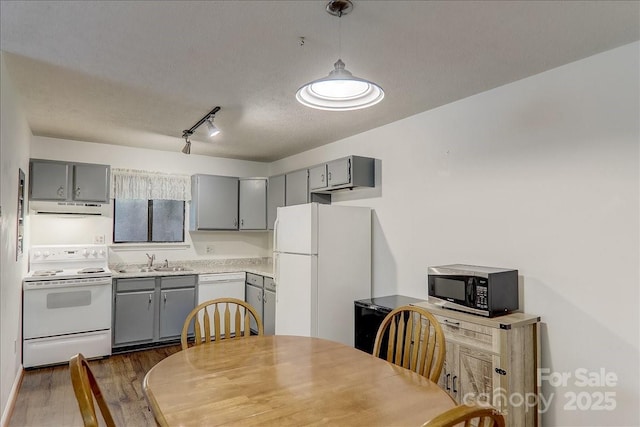 kitchen featuring gray cabinetry, sink, white appliances, and ventilation hood