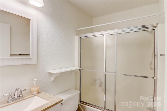 bathroom featuring vanity, a shower with shower door, and toilet