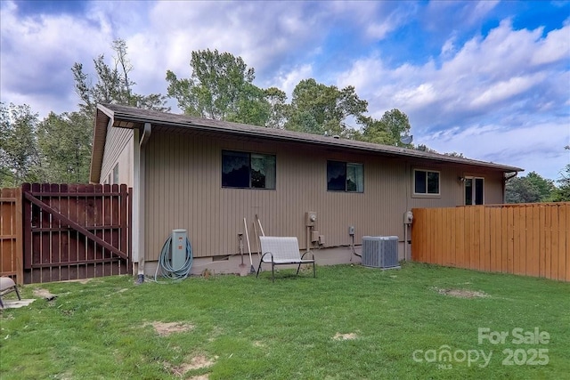 back of house featuring a yard and central AC