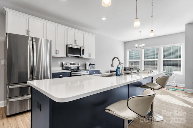 kitchen featuring hanging light fixtures, an island with sink, stainless steel appliances, white cabinets, and a chandelier