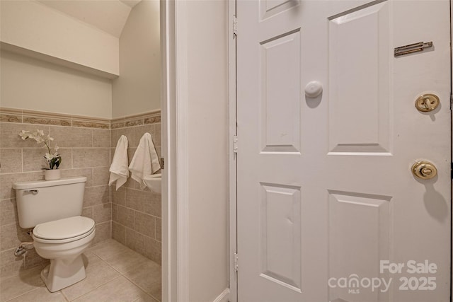 bathroom with tile patterned flooring, toilet, and tile walls