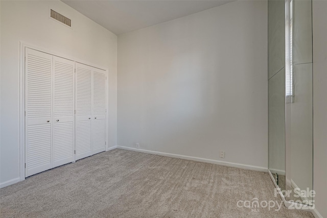 unfurnished bedroom with light carpet and a closet