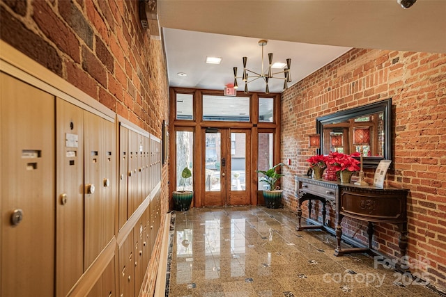 foyer with french doors, brick wall, and an inviting chandelier