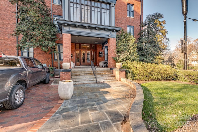 view of exterior entry featuring french doors and a yard