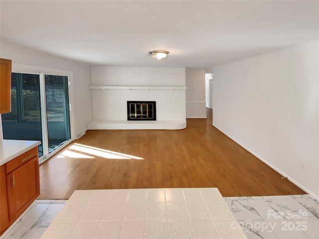 unfurnished living room with light hardwood / wood-style flooring and a brick fireplace