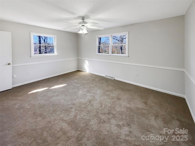 unfurnished room with ceiling fan and dark colored carpet