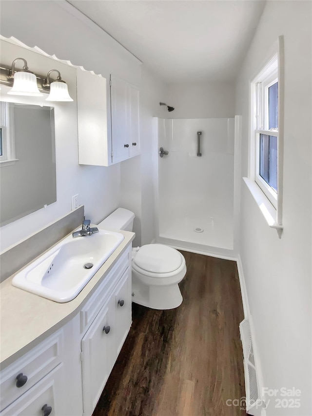 bathroom featuring toilet, hardwood / wood-style floors, vanity, and walk in shower