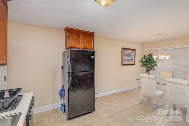 kitchen featuring sink, a notable chandelier, refrigerator, pendant lighting, and a textured ceiling