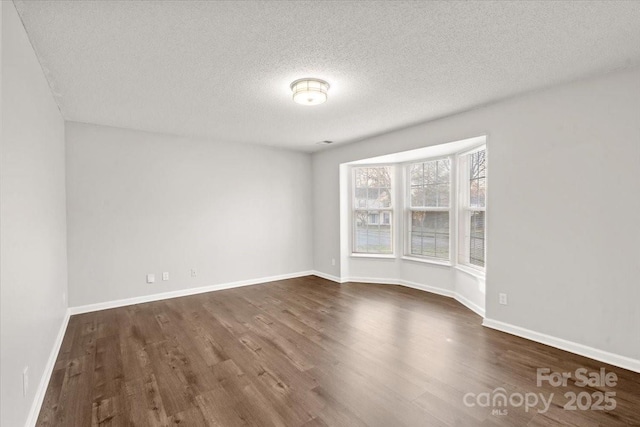 empty room with a textured ceiling and dark wood-type flooring