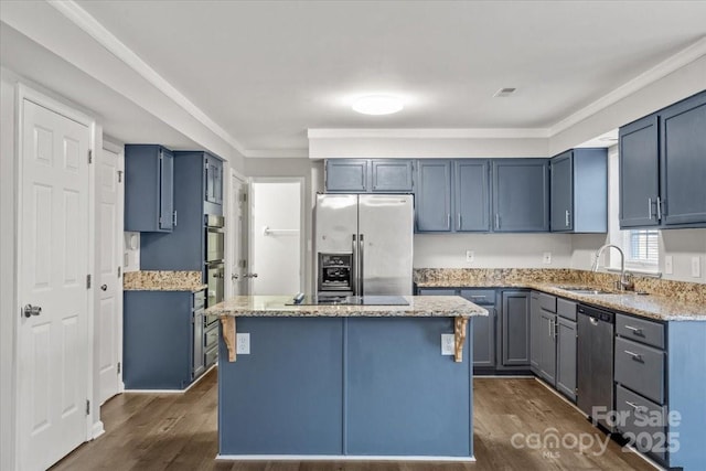 kitchen featuring ornamental molding, stainless steel appliances, dark wood-type flooring, sink, and a center island