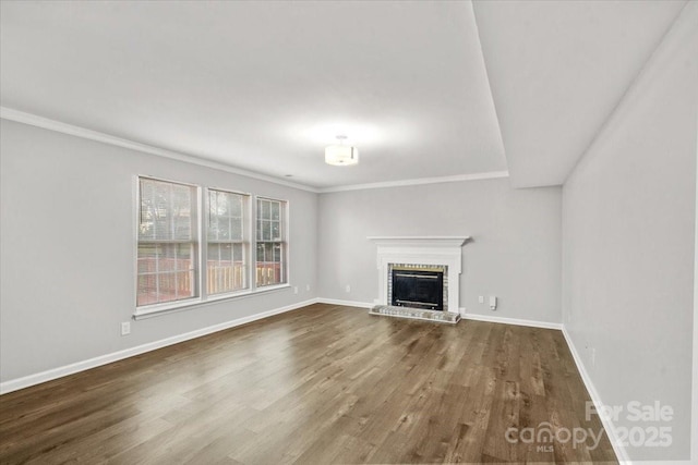 unfurnished living room with hardwood / wood-style floors, crown molding, and a fireplace