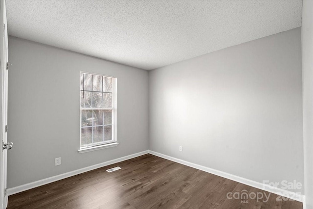 unfurnished room featuring dark hardwood / wood-style flooring and a textured ceiling