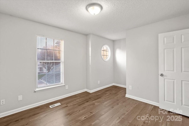 unfurnished room featuring hardwood / wood-style floors, plenty of natural light, and a textured ceiling