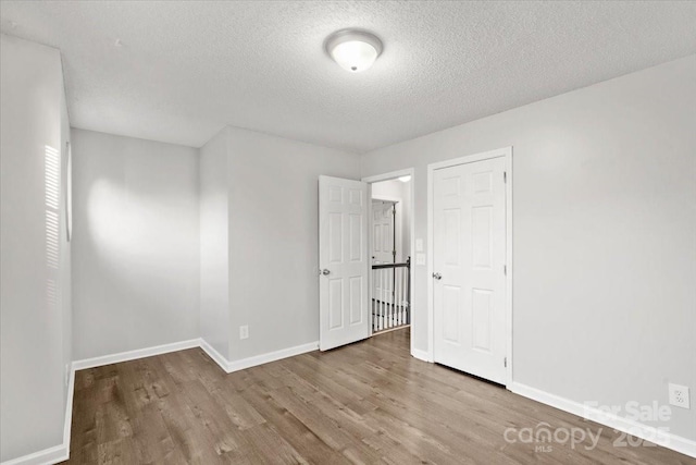 unfurnished room with light hardwood / wood-style floors and a textured ceiling